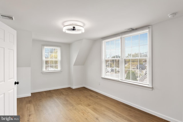 additional living space featuring vaulted ceiling and light wood-type flooring