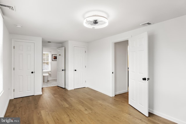 unfurnished bedroom featuring light hardwood / wood-style flooring and ensuite bath