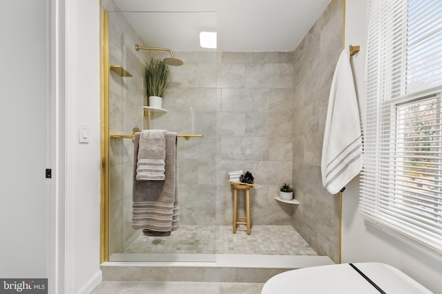 bathroom with tile patterned flooring, a tile shower, and toilet