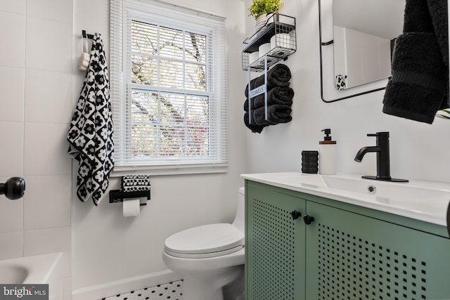 bathroom with a bathing tub, vanity, toilet, and tile patterned floors