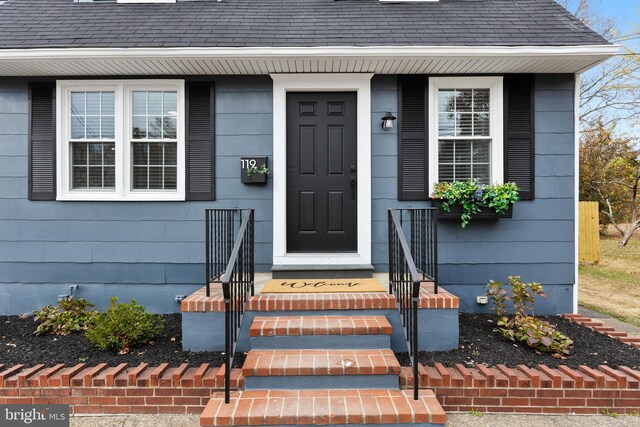 view of exterior entry featuring a shingled roof