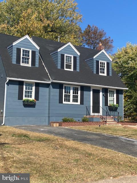 cape cod house featuring a front yard