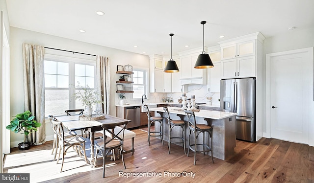 kitchen featuring white cabinets, a kitchen island, dark hardwood / wood-style floors, pendant lighting, and stainless steel appliances