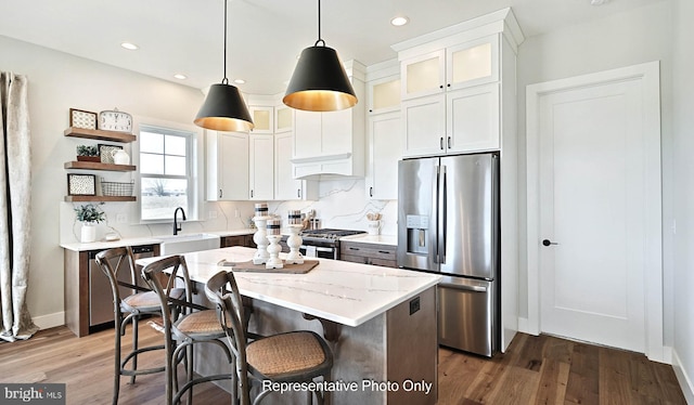 kitchen with dark wood-type flooring, stainless steel appliances, a center island, pendant lighting, and white cabinetry