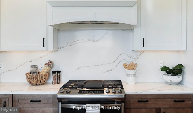 kitchen with white cabinetry, light stone countertops, stainless steel range with gas stovetop, and custom exhaust hood