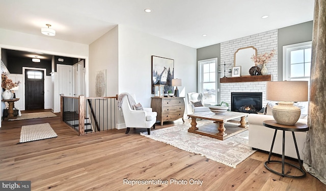 living room with hardwood / wood-style flooring, a wealth of natural light, and a brick fireplace