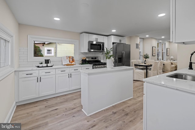 kitchen with sink, appliances with stainless steel finishes, light wood-type flooring, and white cabinetry