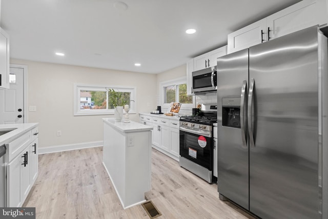 kitchen featuring appliances with stainless steel finishes, white cabinets, and a wealth of natural light