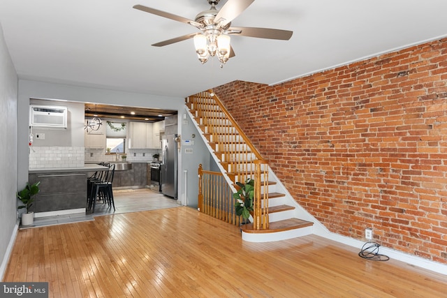 interior space featuring ceiling fan, hardwood / wood-style flooring, a wall mounted air conditioner, sink, and brick wall