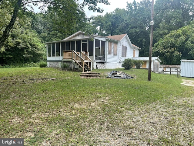 back of house with a shed, a lawn, and a sunroom