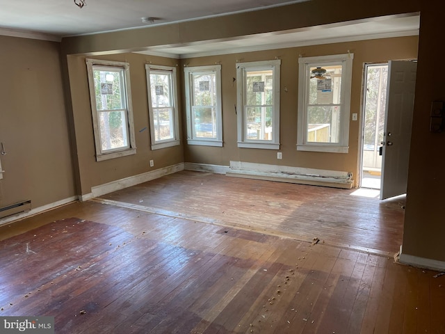 empty room featuring a wealth of natural light, hardwood / wood-style floors, ornamental molding, and baseboards