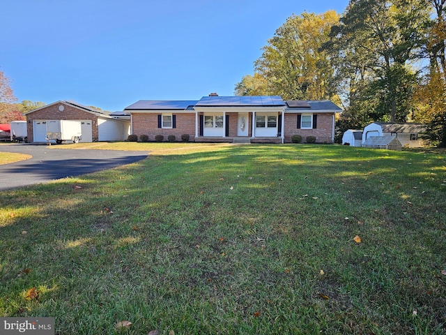 single story home featuring a storage shed, a front lawn, a porch, and solar panels