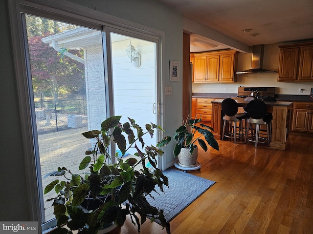 kitchen featuring hardwood / wood-style floors, a kitchen breakfast bar, and wall chimney exhaust hood