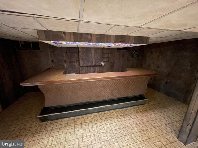 bar featuring a drop ceiling and wood walls