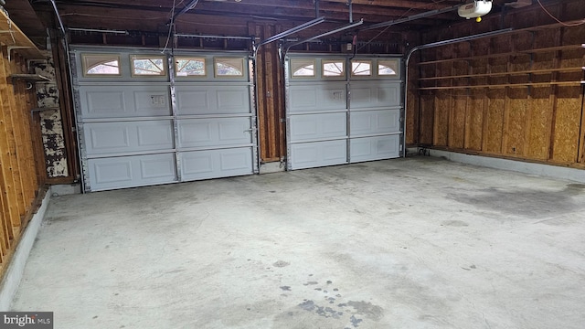 garage with a garage door opener and wooden walls