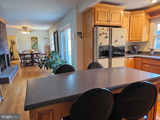 kitchen with a wealth of natural light, a fireplace, light hardwood / wood-style floors, and white fridge with ice dispenser