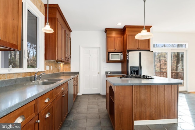 kitchen with a center island, sink, dark tile patterned floors, decorative light fixtures, and stainless steel appliances