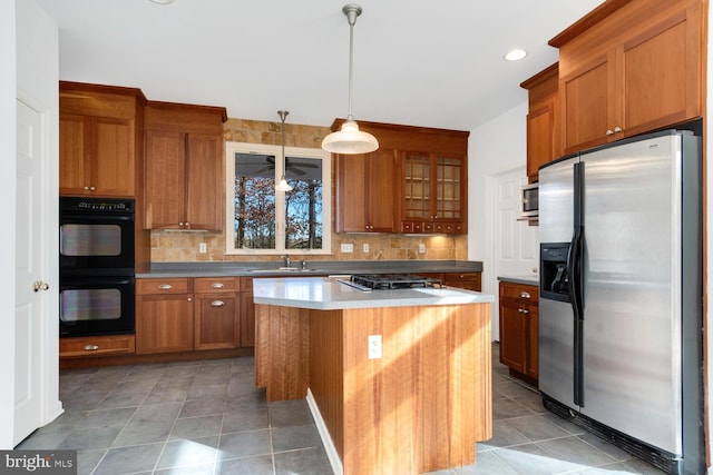 kitchen with appliances with stainless steel finishes, a center island, tasteful backsplash, and pendant lighting