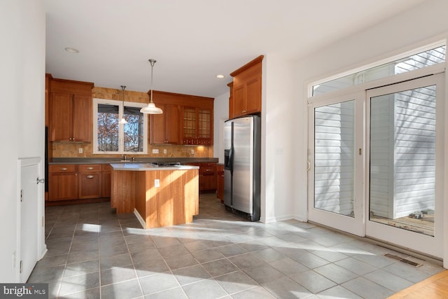 kitchen with decorative backsplash, light tile patterned floors, appliances with stainless steel finishes, decorative light fixtures, and a kitchen island