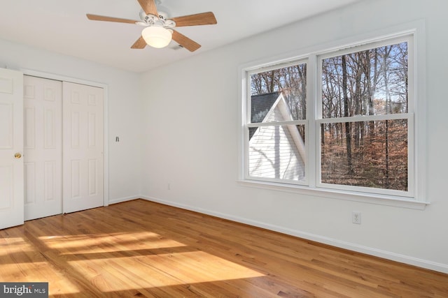 unfurnished bedroom with ceiling fan, a closet, and light wood-type flooring