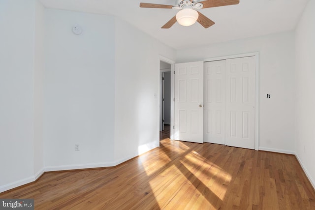 unfurnished bedroom featuring ceiling fan, wood-type flooring, and a closet