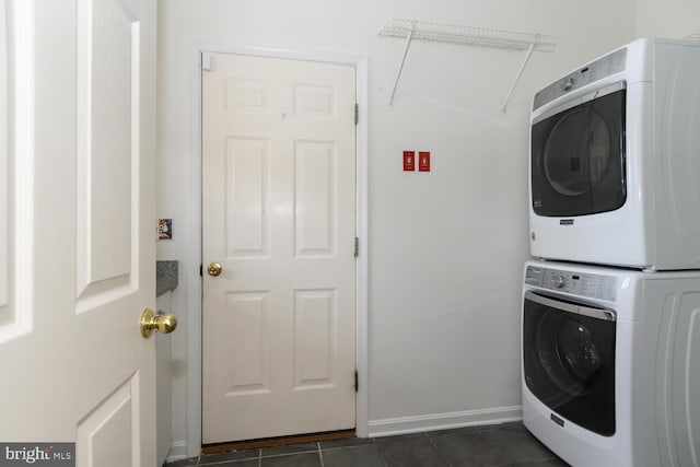 laundry room with dark tile patterned flooring and stacked washer and clothes dryer