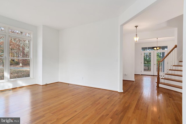 spare room with hardwood / wood-style flooring and an inviting chandelier