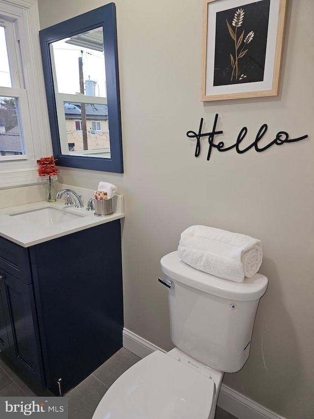 bathroom with tile patterned flooring, vanity, a healthy amount of sunlight, and toilet