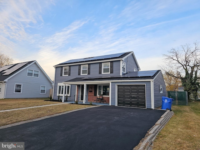 view of front of home featuring a front yard, a porch, and solar panels