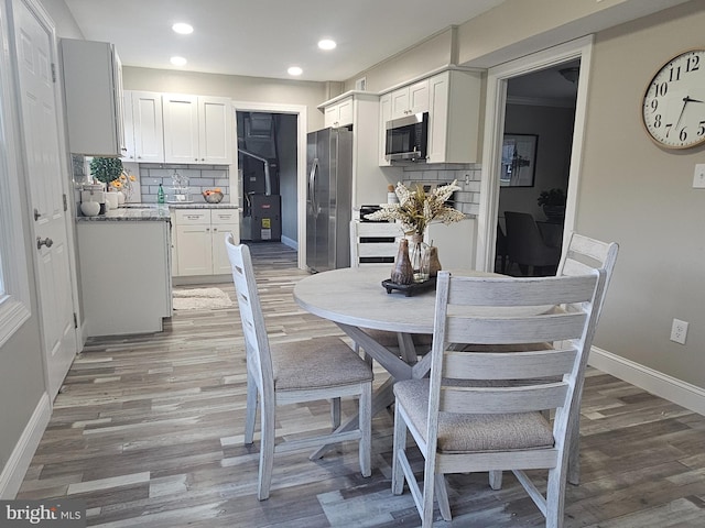 kitchen featuring decorative backsplash, light stone counters, stainless steel appliances, hardwood / wood-style flooring, and white cabinets