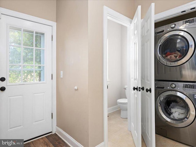 laundry room with light hardwood / wood-style flooring and stacked washing maching and dryer