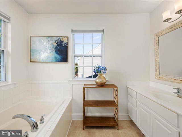 bathroom featuring vanity, a healthy amount of sunlight, tiled tub, and tile patterned flooring