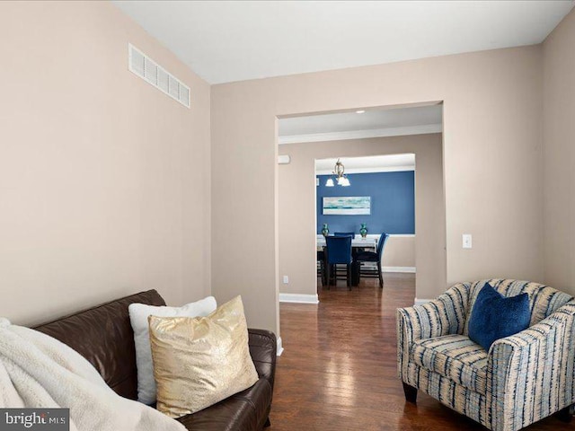 sitting room featuring dark wood-type flooring, crown molding, and an inviting chandelier