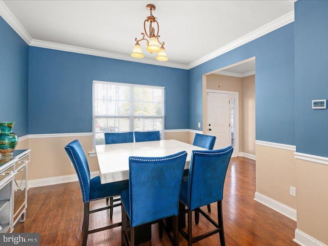 dining area with dark wood-type flooring, crown molding, and an inviting chandelier