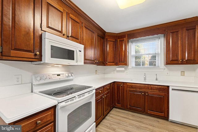 kitchen featuring white appliances, light hardwood / wood-style floors, and sink