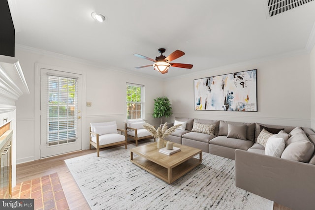 living room with ornamental molding, light wood-type flooring, and ceiling fan