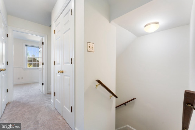 hall featuring lofted ceiling and light colored carpet