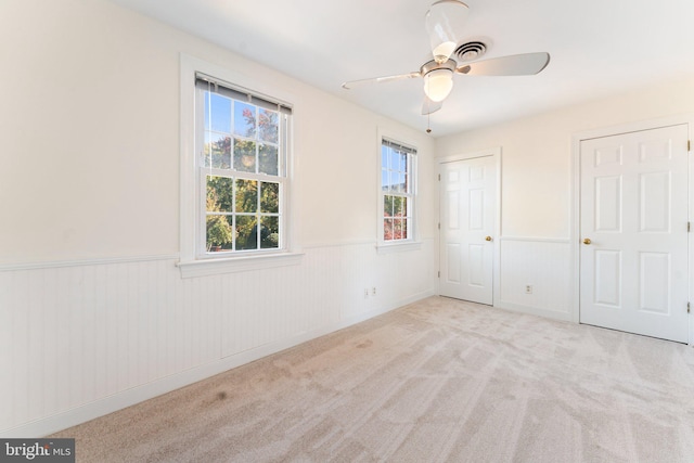 unfurnished bedroom with wood walls, light colored carpet, and ceiling fan