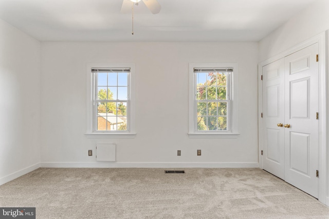 spare room with ceiling fan, a healthy amount of sunlight, and light colored carpet