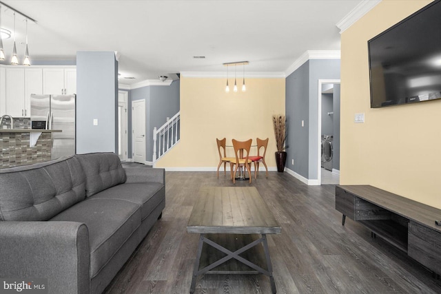 living room with washer / dryer, ornamental molding, an inviting chandelier, and dark hardwood / wood-style flooring