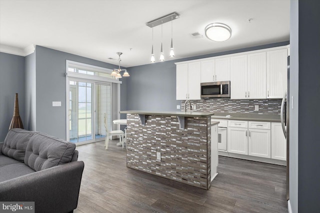 kitchen featuring a kitchen island with sink, white cabinets, pendant lighting, and dark hardwood / wood-style flooring