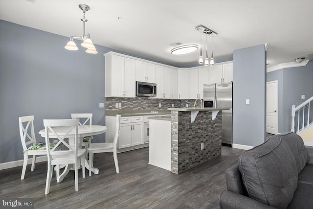 kitchen featuring dark wood-type flooring, an island with sink, hanging light fixtures, and stainless steel appliances