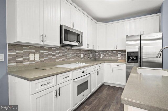 kitchen with tasteful backsplash, sink, dark hardwood / wood-style flooring, white cabinetry, and stainless steel appliances