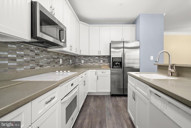 kitchen featuring sink, backsplash, stainless steel appliances, white cabinets, and dark wood-type flooring