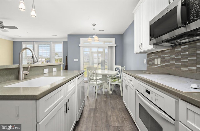 kitchen with white appliances, white cabinetry, decorative light fixtures, and sink