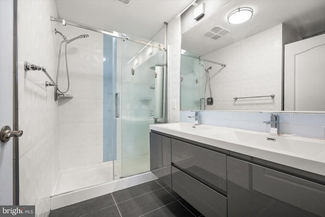 bathroom with vanity, decorative backsplash, a shower with shower door, and tile patterned flooring