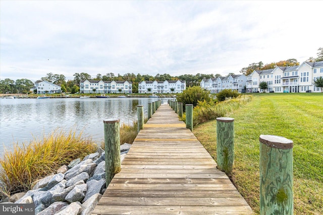 view of dock featuring a lawn and a water view