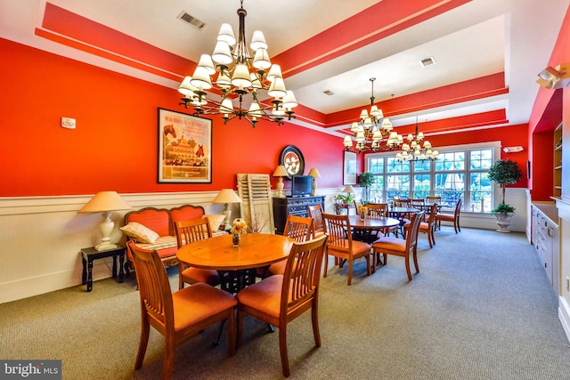 carpeted dining room featuring a notable chandelier and a tray ceiling