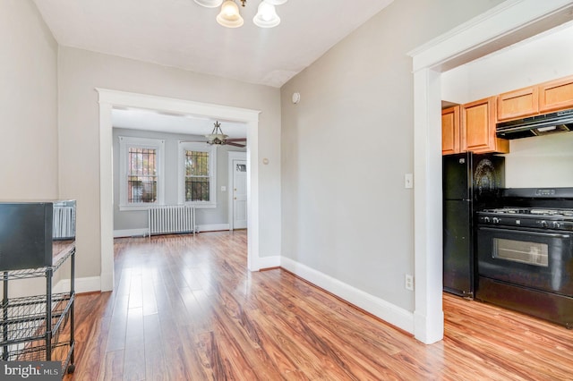 kitchen featuring black appliances, ceiling fan, light wood-type flooring, and radiator