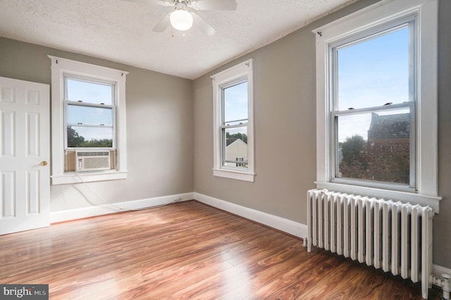 unfurnished room featuring dark wood-type flooring, a textured ceiling, radiator, and ceiling fan